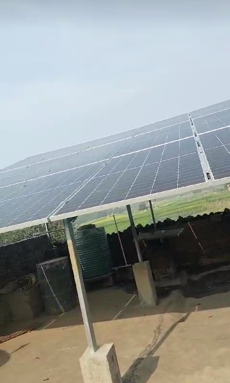 Rural rooftop solar deployment with water tank and farmland in background